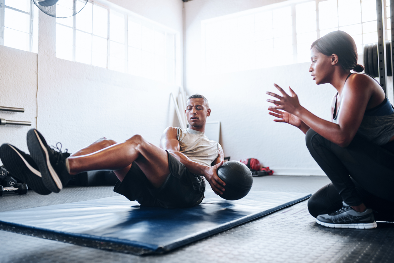 Shot of a man working out with the help of his coach at the gym. A man doing APRE training reps with his coach cheering him on