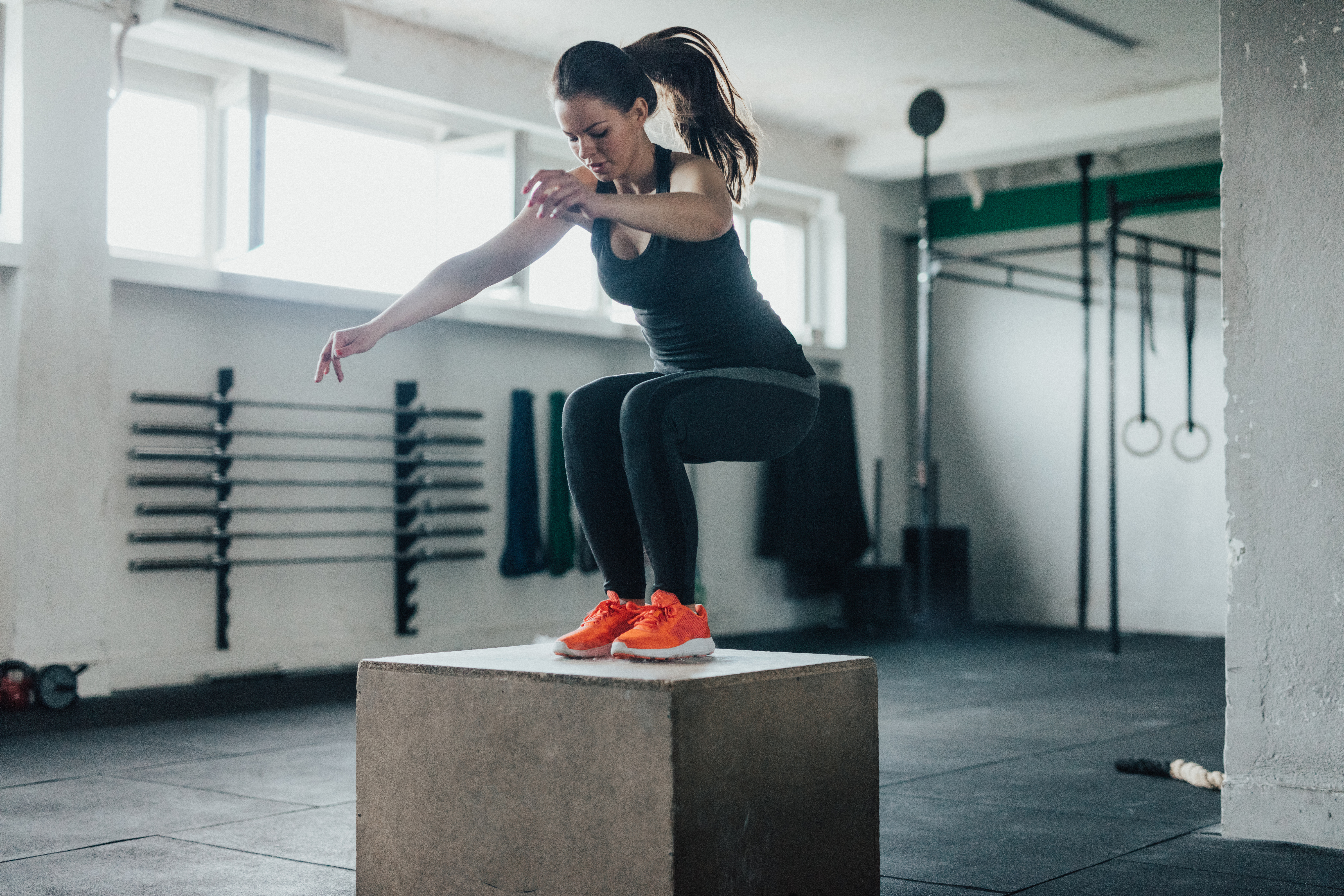Attractive woman jump on a crate in a gym